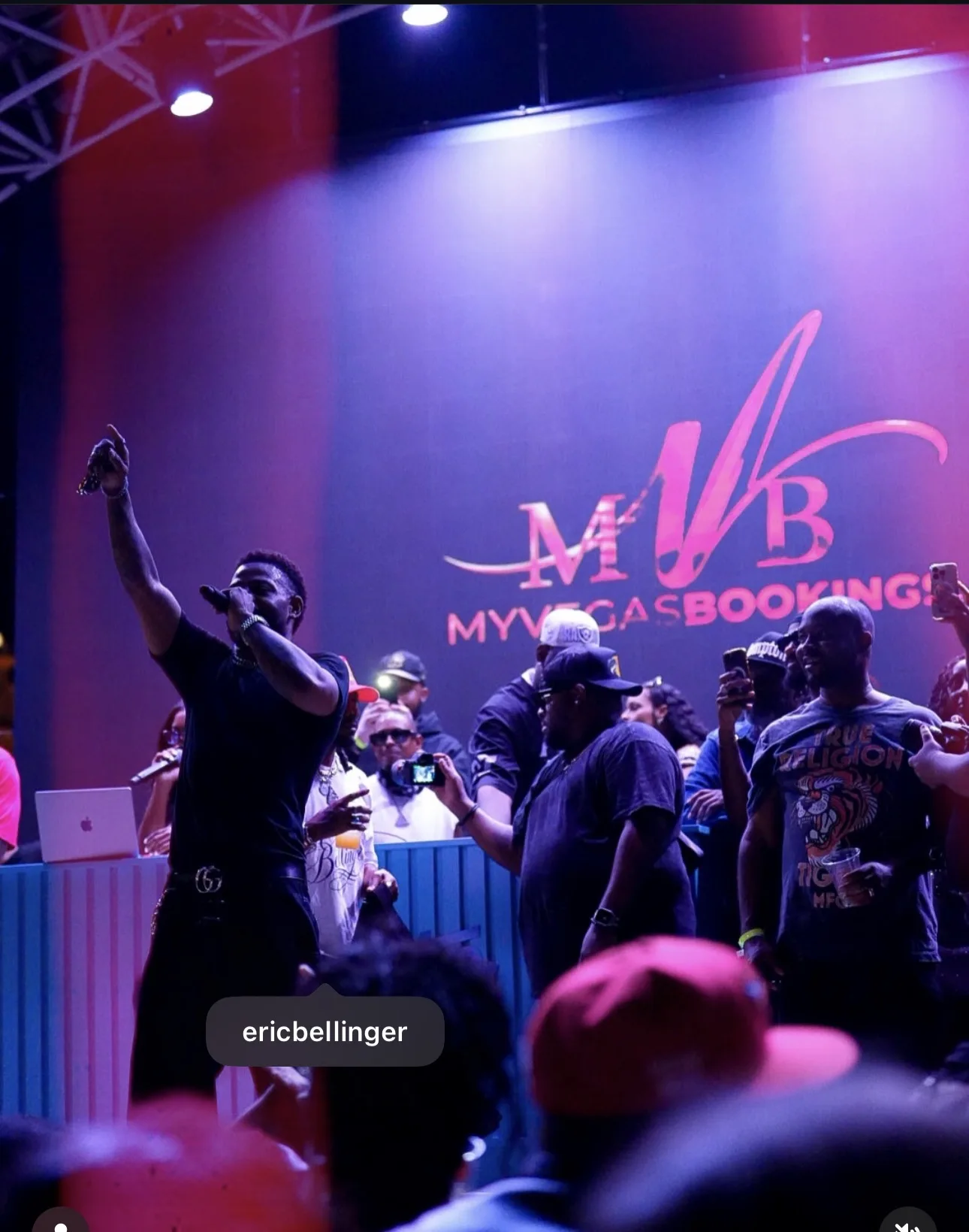 Performer holding a microphone on stage in front of a MyVegasBookings display