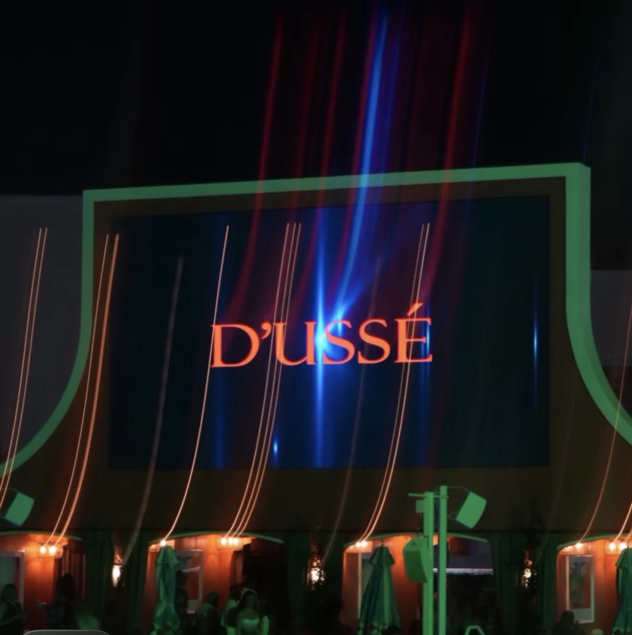 Illuminated D’USSÉ sign above an outdoor event space